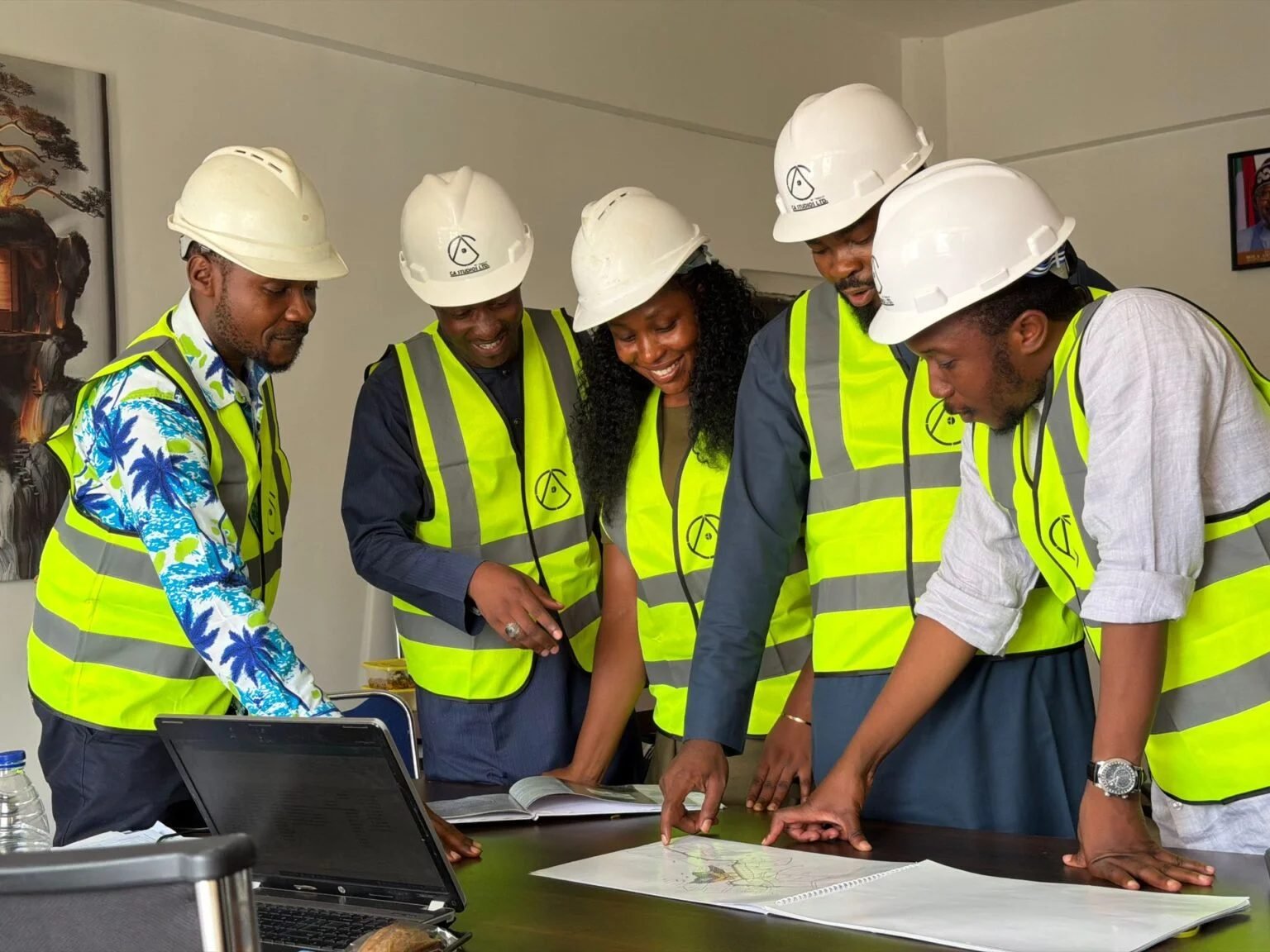 Engineers in helmets and high-visibility vests reviewing drawings