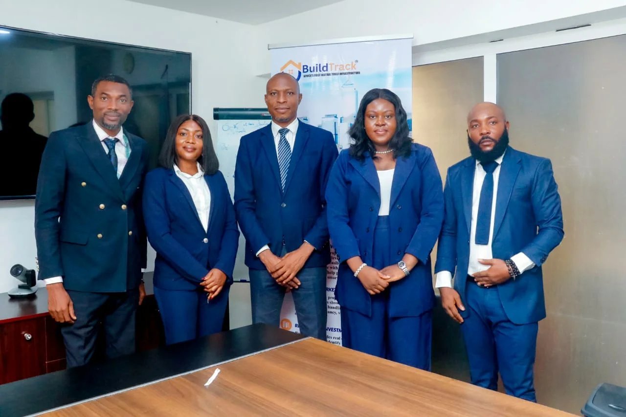 BuildTrack leadership team in navy suits standing in front of a BuildTrack banner in the Abuja boardroom
